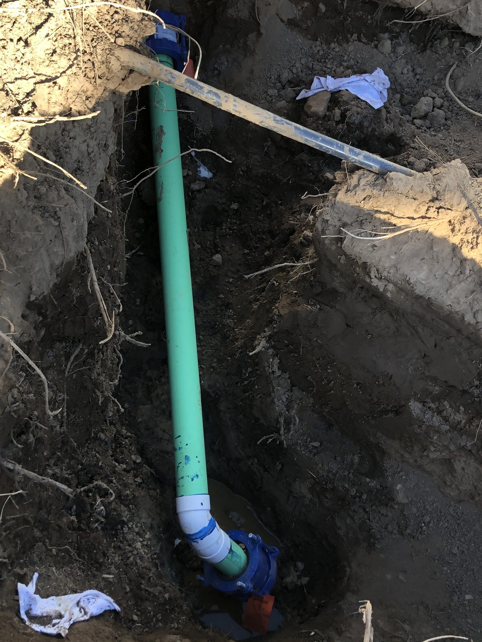 Sewer Line Tie-In — New SDR 35 sewer line being tied into the main, with proper bedding before backfill.